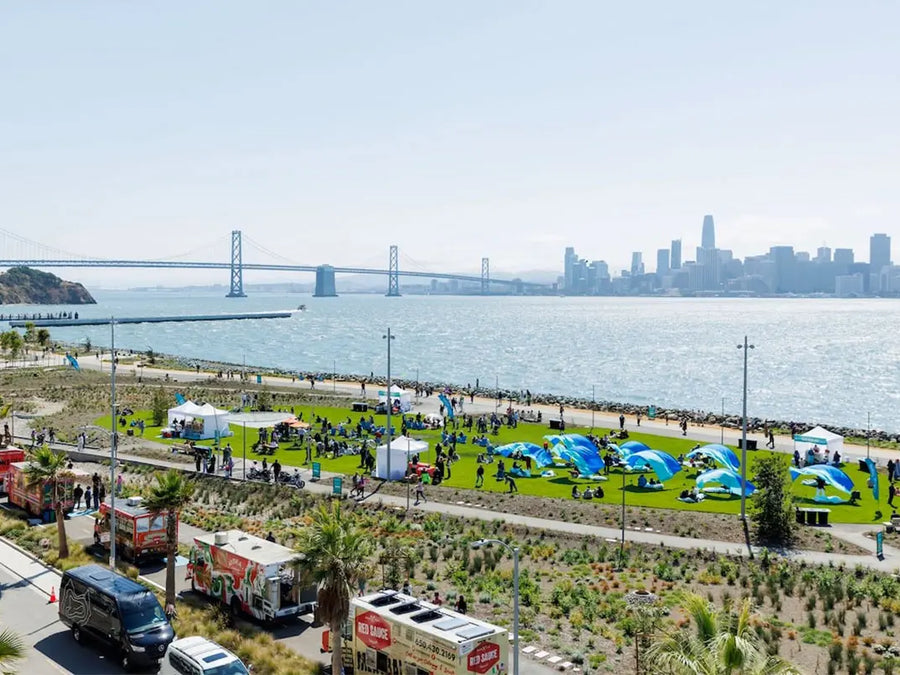 Off the Grid food festival on Treasure Island with food trucks, crowds on the lawn, and San Francisco skyline across the Bay